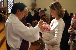Deacon Arthur Alunday blesses Madelyn Meyer while she is being held by her mother, Mary Meyer, during a Dec. 7 Mass at St. Mary Church in Greensburg. Deacon Alunday ministers at St. Mary Parish, where the Meyers are members. (Photo by Sean Gallagher) 