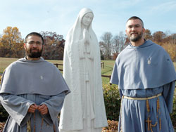Franciscans of the Immaculate Father Jacinto Mary Chapin, left, vocation director, and Father Elias Mary Mills, father guardian of the Marian Friary of Our Lady Coredemptrix, stand beside a statue of Mary on Nov. 6 at Mother of the Redeemer Retreat Center near Bloomington. Franciscan Father Joachim Mary Mudd and five Franciscan Sisters of the Immaculate also minister at the retreat center. The friar’s order was founded in Italy in 1970 and granted pontifical status in 1998. The sisters’ order was founded in 1985. (Photo by Mary Ann Wyand) 