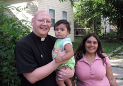 As he walked through the neighborhood of St. Anthony Parish in Indianapolis on Sept. 16, Father John McCaslin met Maria Carlos and her daughter, Jennifer. Father McCaslin is the pastor of St. Anthony and Holy Trinity parishes, two parishes which are using their combined efforts to make a difference in a struggling area of the city. (Photo by John Shaughnessy) 