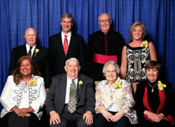 Spirit of Service winners, seated from left, are Maria Pimentel-Gannon, George Jennings, Maryfrances “Mike” Jennings and Margie Pike. Standing, from left, are Tom Hirschauer Jr., Indiana University head football coach Bill Lynch, Msgr. Joseph F. Schaedel and Julie Molloy. (Photo by Richard Clark)