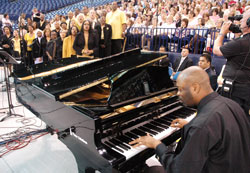 While playing a piano, Vincent Howard leads a choir from Holy Angels Parish in Indianapolis during the May 3, 2009, Mass at Lucas Oil Stadium in Indianapolis celebrating the 175th anniversary of the Archdiocese of Indianapolis. The U.S. bishops recently decided to give each diocese the option of using musical settings of some parts of the new Roman Missal translation beginning in September. (File photo by Sean Gallagher)