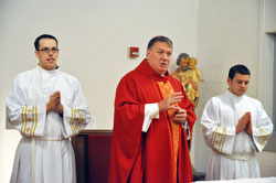 Archbishop Joseph W. Tobin, center, speaks during a Mass on Oct. 18 at Bishop Simon Bruté College Seminary in Indianapolis. Later that day, he was introduced as the sixth archbishop of Indianapolis. Assisting Archbishop Tobin are, left, seminarians Timothy DeCrane, a member of Most Holy Name of Jesus Parish in Beech Grove, and Anthony Stange, a member of St. Lawrence Parish in Lawrenceburg. (File photo by Sean Gallagher)