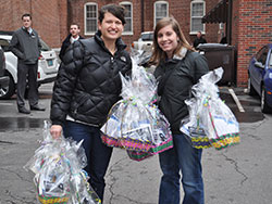 Anne Marie Brummer, left, and Amanda DeRoche smile as they show off the Easter baskets that they helped to deliver to downtown Indianapolis residents during Holy Week. Members of St. John the Evangelist Parish delivered 500 baskets containing chocolate, flowers and faith-related materials to non-Catholics and fallen-away Catholics to invite them to the church. (Submitted photo)