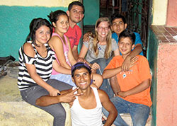 While Jenna Knapp, center of back row, visited gang members in jail and wrote down their stories during her three years in El Salvador, she also volunteered to help younger children avoid that future, teaching them life skills and vocational skills. Here, the 2010 graduate of the University of Notre Dame is pictured on the front steps of the home in the Dolores Medina community where she lived with a family of five headed by a single mother. The house is also where she met with the youths she helped every week. (Submitted photo)