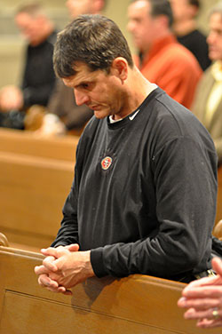 Jim Harbaugh, head coach of the National Football League’s San Francisco 49ers, kneels in prayer during a Feb. 22 Mass at St. John the Evangelist Church in Indianapolis. NFL coaches and team officials from across the country attended the Mass and a dinner that followed. They were in Indianapolis for the annual NFL Scouting Combine, during which NFL draft-eligible college football players display their talents. (Photo by Sean Gallagher)