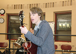 Jackson McLaughlin hits the right notes on guitar while John Rash, in the background, pounds the drums during a practice session of Arisan Maru, the name of the Scecina High School rock band that performs professionally. (Photo by John Shaughnessy)