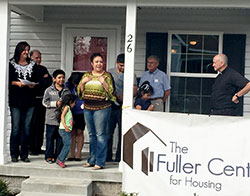 Veronica Villafuerte, center, expresses the gratitude and amazement of her family for the new home they received through the efforts of Sacred Heart of Jesus Parish in Indianapolis, other churches and The Fuller Center for Housing of Central Indiana. Heather Rayka, left, of The Fuller Center for Housing, Franciscan Father Larry Janezic, pastor of Sacred Heart Parish, and Jesuit Father Jeremiah Lynch, associate pastor, far right, share in the moment. (Submitted photo)