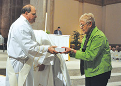 Linda Smith, a member of St. Michael Parish in Bradford, receives holy oils for her New Albany Deanery faith community from Deacon Jeffrey Powell during the archdiocesan chrism Mass on April 11 at SS. Peter and Paul Cathedral in Indianapolis. Deacon Powell ministers at Our Lady of Perpetual Help Parish in New Albany. (Photo by Sean Gallagher)	
