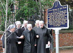 Little Sisters of the Poor Sisters Amy, left, Janet, Gloria, Marthe, Cecilia and Mother Mary Vincent pose on May 20 with a state historical marker that was unveiled on that day at 520 E. Vermont St. in Indianapolis, where the order’s first home for the elderly poor in Indianapolis was located from 1873-1967. (Photo by Natalie Hoefer)