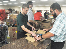Seminarians Samuel Rosko, left, and Michael Dedek box drinks on Aug. 8 at the Society of St. Vincent de Paul’s Pratt-Quigley Client Choice Food Pantry in Indianapolis. The morning of volunteer service at the pantry took place during the annual archdiocesan seminarian convocation. (Photo by Sean Gallagher)