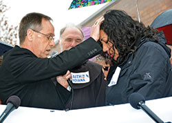 Archbishop Charles C. Thompson prays over Erika Fierro outside of the Department of Homeland Security office in Indianapolis on April 24 prior to her meeting asking for a ‘credible fear interview.’ Also pictured is Franciscan Father Larry Janezic. (Photo by Natalie Hoefer)