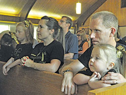 Tessa Guillaume, left, kneels in prayer during the June 24 anniversary Mass to celebrate the 50th anniversary of the founding of St. Isidore the Farmer Parish in Perry County, with her parents, Stacey and Ty Guillaume, and her sister, Serena Guillaume. (Photo by Sean Gallagher)