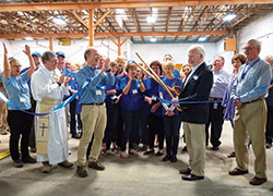 Volunteers and supporters cheer as John Ryan, president of the Indianapolis St. Vincent de Paul Council, uses a large pair of scissors to cut a ribbon in celebration of the opening of the new warehouse location of the Bloomington Society of St. Vincent de Paul on April 11. The society recently upgraded to this 9,500 square foot building after operating in a location with 7,500 square feet. (Photo by Katie Rutter)