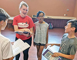 Alicia Popson enjoys a moment of joy with sixth-grade students Graham Sillings, left, Adilene Torres and Noah Geswein at St. Mary-of-the-Knobs School in Floyd County as she helps them prepare for a play. (Submitted photo)