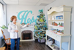 April Haskett, executive director of Hope Resource Center in Bedford, points out the cabinet of free items in the pregnancy care center’s welcoming lobby on a day when those served by the organization were invited to come to the facility for free family Christmas photo shoots on Nov. 23, 2022. (Photo by Natalie Hoefer)