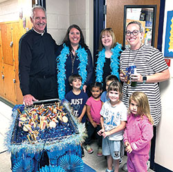 Members of the community of St. Charles Borromeo School in Bloomington celebrate on Sept. 19 the U.S. Department of Education naming it a 2023 Blue Ribbon School. Father Thomas Kovatch, pastor of St. Charle Borromeo Parish, left, joins Victoria Arther, principal, Amy Terry, assistant principal, and pre-kindergarten teacher Elizabeth Wilson. Pre-kindergarten students Thomas Bowling, left, Nazeli Kassamanian, Jack Becker (partially obscured), Melanie Levis and Layla Messel join in the celebration. (Submitted photo)