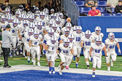The football team of Bishop Chatard High School in Indianapolis runs onto the field of Lucas Oil Stadium in Indianapolis on Nov. 24, the day when the Trojans defeated the team from Heritage Hills High School to win Indiana’s Class 3A championship. (Submitted photo)