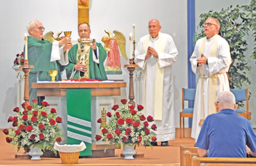 Deacon Steven Gretencord, left, and Archbishop Charles C. Thompson lift the chalice and paten during a Mass in Sacred Heart of Jesus Church in Terre Haute celebrating the faith community’s 100th anniversary on June 8. Deacon Gretencord, a son of the parish, was a member of the first class of deacons ordained in the archdiocese in 2008. Father Stephen Giannini, second from right, served as pastor of the parish from 1997-2002 and as its priest moderator from 2010-2013. Father Darvin Winters, right, served as the parish’s pastor from 2005-2010 and now serves as its sacramental minister. (Photo by Natalie Hoefer)