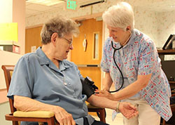 Benedictine Sister Anna Marie Brosmer takes the blood pressure of Sister Mary Victor Kercher in the Hildegard Health Center at Monastery Immaculate Conception in Ferdinand.