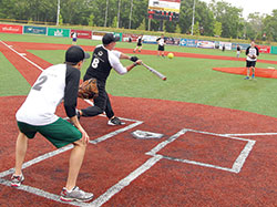 Priests and seminarians of the Lafayette diocese play in the first Men In Black Serra Series softball game on June 4 at the Kokomo Municipal Stadium. Hundreds of fans turned out for the event, despite the rainy weather. Proceeds from the game benefited the diocesan Seminarian Fund. (Photo by Bob Nichols)