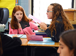 Nativity of Our Savior seventh-graders Angie Radoe (left) and Ava Sykes read letters received from their St. John Bosco of Hammond peer penpals, at the Portage school on Nov. 11. The exchange helps the youths communicate through writing. (Anthony D. Alonzo photo)