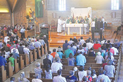 Archbishop Charles C. Thompson raises the Eucharist during Mass at Our Lady of Perpetual Help Church in New Albany on July 30. (Photo by Sean Gallagher)