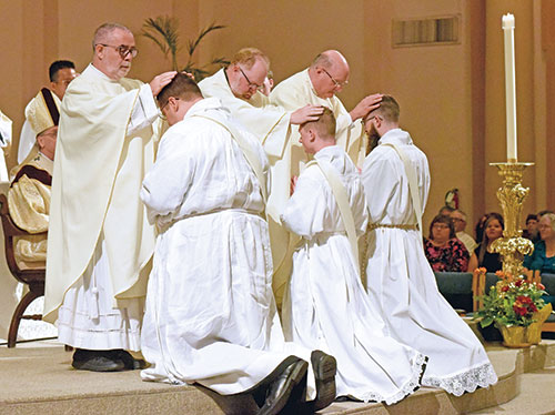 Father Joseph Moriarty, left, Father Joseph Newton and Msgr. William F. Stumpf, ritually lay hands respectively on transitional deacons Anthony Armbruster, Samuel Rosko and Bobby Vogel during a June 1 Mass at SS. Peter and Paul Cathedral in Indianapolis in which the three deacons were ordained archdiocesan priests. (Photo by Sean Gallagher)