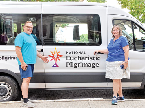 Jeff and Nora Grasser, members of St. Louis de Montfort Parish in Fishers, Ind. (Lafayette Diocese), pose by one of the National Eucharistic Pilgrimage vans outside of St. Joseph University Church in Terre Haute on July 12. By taking part in adoration and a eucharistic procession in Terre Haute, Nora fulfilled her desire to participate in each of the four national pilgrimage routes. (Photo by Natalie Hoefer)