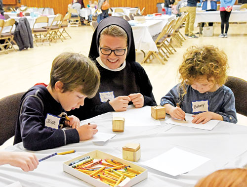 Franciscan Sister Mary Amata Naville smiles while watching Joseph and Bethany Bedwell color at a booth during the Family Day for Vocations on Jan. 18 at the Archbishop Edward T. O’Meara Catholic Center in Indianapolis. Joseph and Bethany are members of St. John the Evangelist Parish in Indianapolis. (Photo by Sean Gallagher)