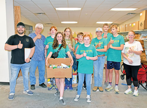 At left, Evan Wise, youth minister for St. Bernard Parish in Frenchtown, St. Joseph Parish in Crawford County and St. Michael Parish in Bradford, poses with youths of the parishes and an adult chaperone at right on June 17 at Harrison County Community Services (HCCS) in Corydon, where the group prepared boxes of food for delivery to the homebound as part of the New Albany Deanery’s Summer Daze program. Second from left is Deacon Rick Cooper, executive director of HCCS. (Photo by Natalie Hoefer)