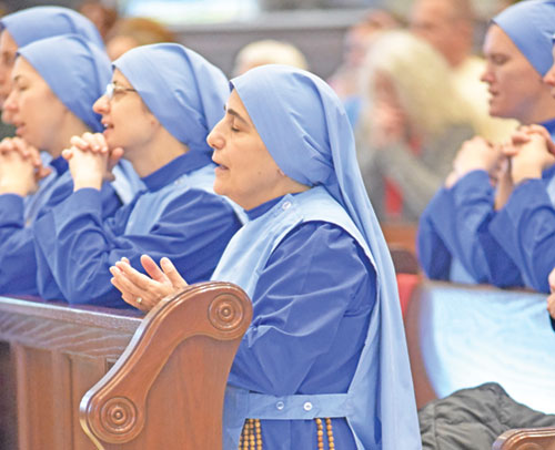 With members of the Daughters of Mary of Nazareth beside her, Mother Olga of the Sacred Heart kneels in prayer during a Dec. 14, 2025, Mass at St. John Paul II Church in Sellersburg. Born in Iraq, Mother Olga founded the religious community in 2011 in the Archdiocese of Boston. Two of its members are beginning ministry at St. John Paul II Parish. (Photo by Sean Gallagher)
