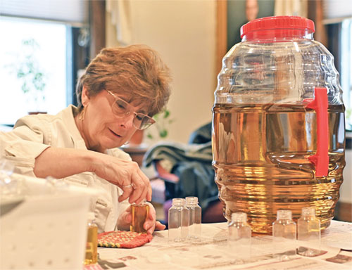 Keri Carroll, executive assistant at SS. Peter and Paul Cathedral Parish in Indianapolis, helps bottle chrism oil on March 16. The oil will be distributed to all archdiocesan parishes during the annual chrism Mass at the cathedral on March 31. (Photo by Emily Mastronicola)