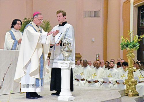 Archbishop Charles C. Thompson blesses the oil of the sick on March 31 at SS. Peter and Paul Cathedral in Indianapolis during the archdiocese&rsquo;s annual chrism Mass. Assisting him at right is seminarian John Fritch, a member of St. Martin of Tours Parish in Martinsville. Standing at left is transitional Deacon Timothy Khuishing, who ministers at St. Mark the Evangelist Parish in Indianapolis. (Photo by Sean Gallagher)
