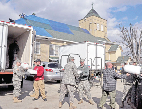 Members of the Indiana National Guard and other rescue workers haul donated ice to a refrigerated truck parked beside St. Francis Xavier Church in Henryville on March 3, 2012. The previous day, a tornado ravaged the southern Indiana town. As the coordinator of disaster preparedness and response for the archdiocese&rsquo;s Catholic Charities, Jane Crady has responded to this natural disaster and many others in Indiana and around the United States in the past 20 years. (File photo by Sean Gallagher)