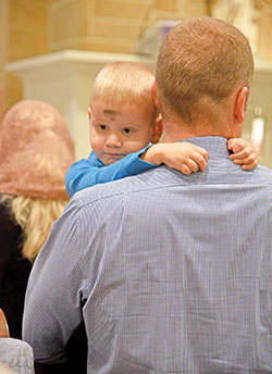 Dan Hollowell holds his son Michael during an Ash Wednesday Mass on Feb. 14 at Our Lady of the Most Holy Rosary Church in Indianapolis. (Photo by Sean Gallagher)