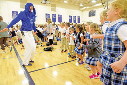 Wearing a blue wig, Rebecca Stone, principal of SS. Francis and Clare of Assisi School in Greenwood, celebrates on Sept. 23, 2024, with students of the school. The celebration took place after she announced to the students that the U.S. Department of Education had named SS. Francis and Clare a National Blue Ribbon School. (Photo by Sean Gallagher)