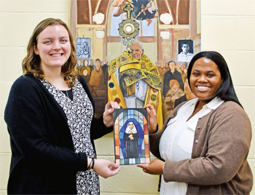 Rachel Levy, left, and Cheyenne Johnson pose in the Archbishop Edward T. O’Meara Catholic Center in Indianapolis on March 6 with an image of St. Katharine Drexel, the saint for whom the 2025 National Eucharistic Pilgrimage route is named. Levy, archdiocesan coordinator of young adult ministry, and Johnson, director of Catholic campus ministry at Butler University in Indianapolis, are among the eight young adults selected nationally to be perpetual pilgrims on the 3,300-mile pilgrimage, which departs Indianapolis on May 18 and arrives in Los Angeles on June 22. (Photo by Natalie Hoefer)