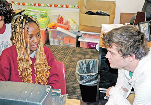 Brayden Lowery helps guide fifth-grade student Aamber Chikati through an art project on March 17, two days after the teacher at Holy Angels School in Indianapolis competed in the 2025 NCAA Division II National Wrestling Championships in Indianapolis. (Photo by John Shaughnessy)