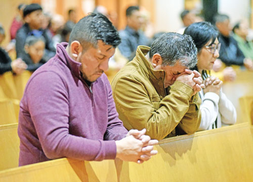 Cesar, left, Julio and Margarita Zuñiga kneel in prayer on Nov. 3, 2023, during a Mass at St. Rita Parish in Indianapolis. (File photo by Sean Gallagher)