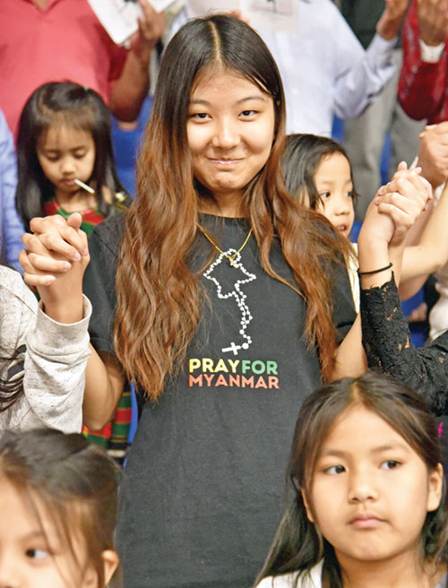 Mary Lian, a member of St. Mark the Evangelist Parish in Indianapolis, holds hands while praying during an April 12 Mass at Roncalli High School in Indianapolis. Burmese Catholics in the archdiocese gathered at the liturgy to pray for their home country of Myanmar, which was struck by a major earthquake on March 28. (Photo by Sean Gallagher)