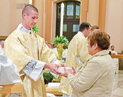 Linda Manis, a member of Prince of Peace Parish in Madison, receives blessed oils from transitional Deacon Isaac Siefker on April 15 during the annual archdiocesan chrism Mass at SS. Peter and Paul Cathedral in Indianapolis. (Photos by Sean Gallagher)