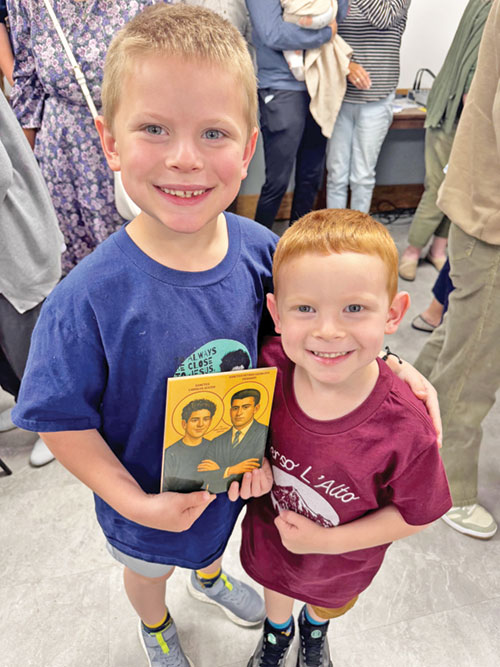 Leo Horine, 7, and his brother Isaac, 5, hold an image of St. Carlo Acutis and St. Pier Giorgio Frassati on Sept. 7 during a watch party held at St. John Paul II Parish in Sellersburg for the canonization of the Church’s two newest saints. (Submitted photo)