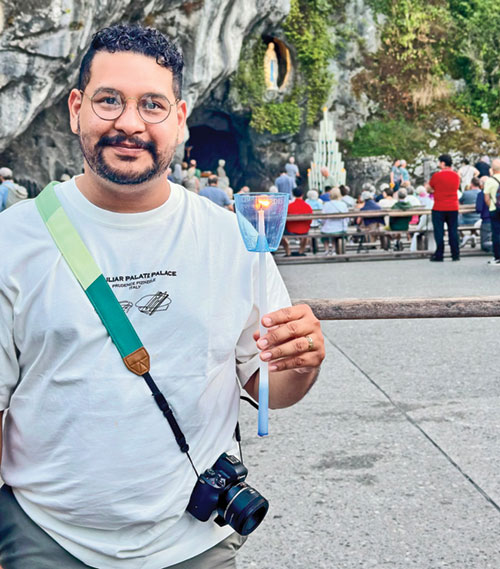 Felix Navarrete, coordinator of the archdiocesan Hispanic Ministry, holds a candle at the shrine to Our Lady at Lourdes in France. (Submitted photo)
