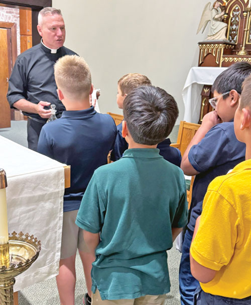 Father Rick Nagel, pastor of Prince of Peace Parish in Madison, teaches fourth-grade students at the faith community&rsquo;s Pope John XXIII School how to be an altar server on Sept. 17, 2025, in St. Patrick Chapel, which is adjacent to the school. (Submitted photo)