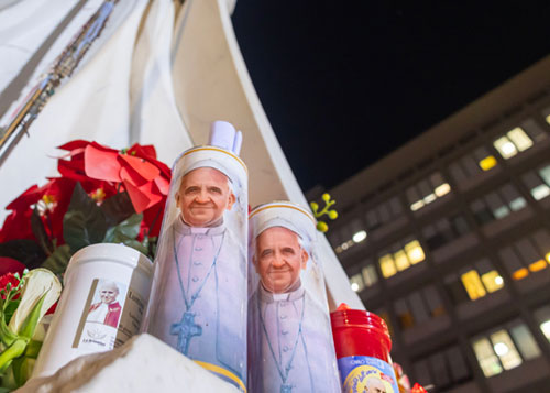 Votive candles and flowers are seen at the base of a statue of St. John Paul II outside Rome's Gemelli hospital Feb. 21, 2025, where Pope Francis is being treated for double pneumonia. (CNS photo/Pablo Esparza)