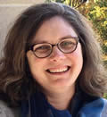 picture of Erin Jeffries, woman with white skin, curly brown hair, and glasses.