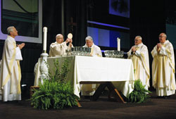 Archbishop Daniel E. Pilarczyk of Cincinnati elevates the Eucharist on March 25 during the opening Mass of the National Catholic Educational Association’s annual convention at the Indiana Convention Center in Indianapolis. Also concelebrating at the altar are, from left, Archbishop Donald W. Wuerl of Washington, Bishop John M. D’Arcy of Fort Wayne-South Bend, Ind.; Bishop Gerald A. Gettelfinger of Evansville, Ind.; and Msgr. Joseph F. Schaedel, vicar general of the Archdiocese of Indianapolis. (Photo by Sean Gallagher) 