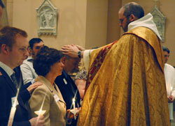 Benedictine Father Julian Peters, administrator pro-tem of SS. Peter and Paul Cathedral Parish in Indianapolis, lays his hands on the head of Russell Jenkins in a celebration of the rite of confirmation during Cathedral Parish’s Easter Vigil on March 22. Jenkins and his wife, Linda, second from left, were received into the full communion of the Church during the liturgy at which their son, transitional Deacon Aaron Jenkins, assisted Father Julian. Russell and Linda Jenkins are members of St. Mary Parish in Rushville. (Photo by Sean Gallagher) 