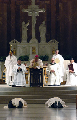 Archbishop Daniel M. Buechlein kneels in prayer on a prie dieu while, from left, deacons Joseph Newton and Aaron Jenkins lay prostrate during the praying of the litany of the saints. The two were ordained to the priesthood on June 7 at SS. Peter and Paul Cathedral in Indianapolis. Assisting Archbishop Buechlein are, from left, seminarian Benjamin Syberg, Ford Cox, the archbishop’s administrative assistant, Benedictine Father Julian Peters, administrator pro-tem of the Cathedral Parish and seminarians Daniel Bedel and Martin Rodriguez. (Photo by Sean Gallagher)