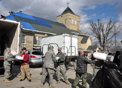 Members of the Indiana National Guard and other rescue workers haul donated ice to a refrigerated truck parked beside St. Francis Xavier Church in Henryville on March 3. The previous day, a tornado ravaged the southern Indiana town. Since the church sustained relatively little damage, it quickly became a place to collect and distribute donated material goods to aid people affected by the storm. (Photo by Sean Gallagher)
